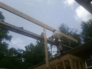 Carpenter setting a ridge beam over a new addition frame — Ice Dam Removal by Roofing Brothers in Kimmell