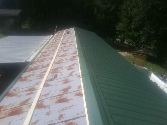 Old rusted panels beside newly installed green metal roofing — Wind Damage Roof Repair by Roofing Brothers in Kimmell