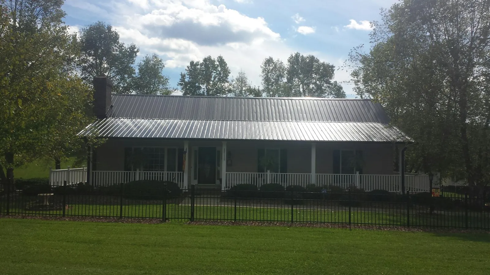 Gray metal roof on a brick ranch with a full width front porch — Gutter Guard Installation work by our crew in Kimmell