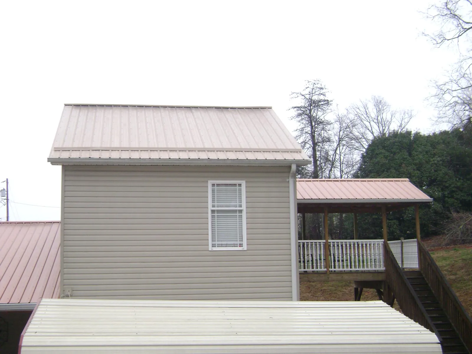 Tan metal roofs on a two story addition and attached porch, from a Roof Replacement job in Kimmell