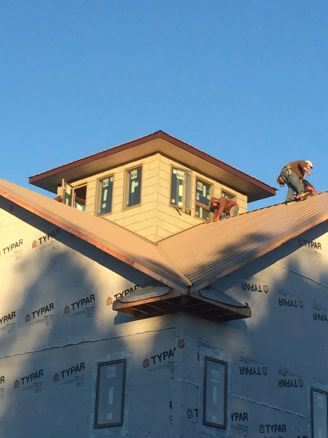 Roofers working around a rooftop cupola on a new metal roof at sunset — Roof Waterproofing in Kimmell by Roofing Brothers